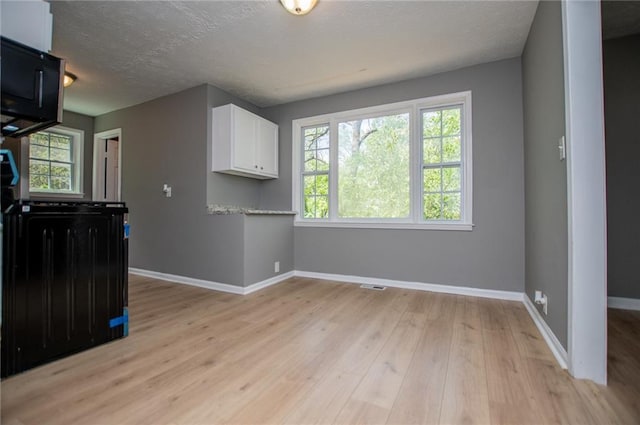 8211 Thompson St, Douglasville, GA 30134 - kitchen with white cabinets, baseboards, light countertops, a textured ceiling, and light wood finished floors