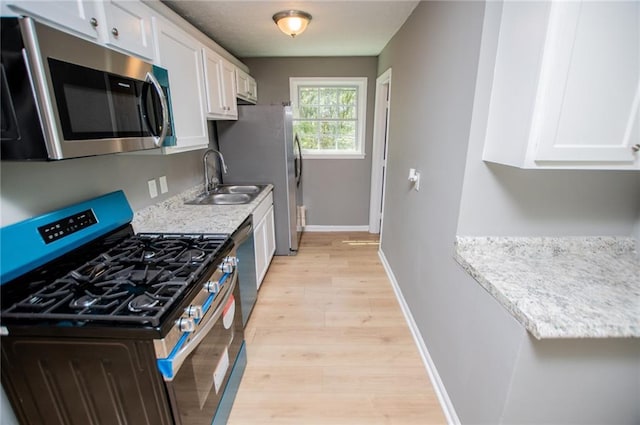 8211 Thompson St, Douglasville, GA 30134 - kitchen with white cabinets, a sink, stainless steel appliances, light wood finished floors, and baseboards
