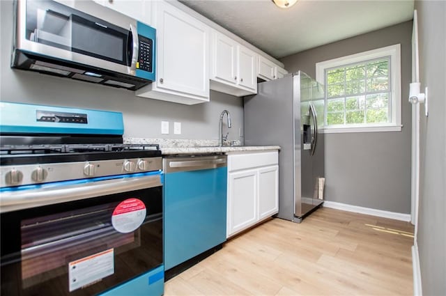 8211 Thompson St, Douglasville, GA 30134 - kitchen with light wood-type flooring, a sink, white cabinets, and stainless steel appliances