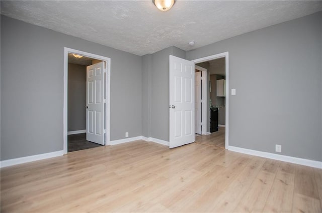 8211 Thompson St, Douglasville, GA 30134 - unfurnished bedroom featuring a textured ceiling, light wood finished floors, and baseboards