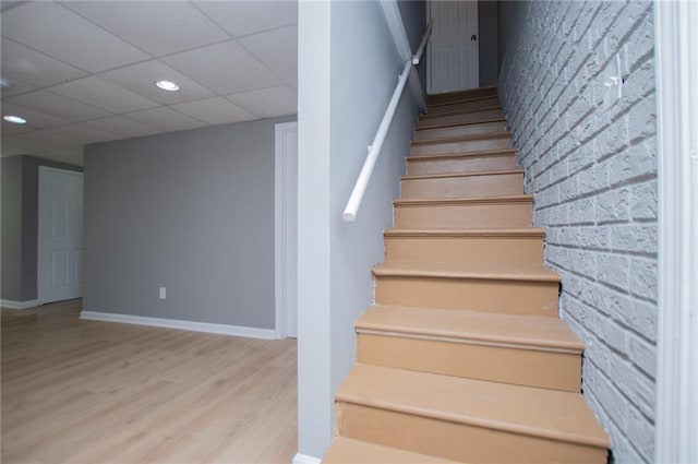 8211 Thompson St, Douglasville, GA 30134 - staircase featuring a drop ceiling, recessed lighting, wood finished floors, brick wall, and baseboards