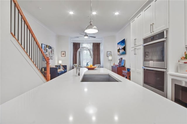 kitchen featuring sink, white cabinetry, hanging light fixtures, double oven, and ceiling fan