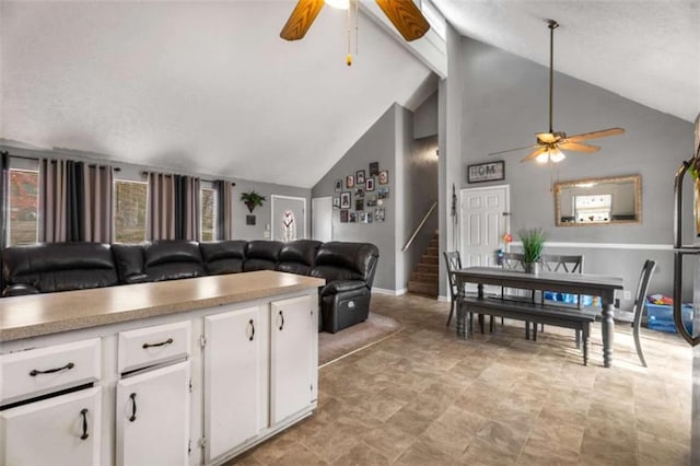 kitchen with open floor plan, white cabinets, light countertops, and a ceiling fan