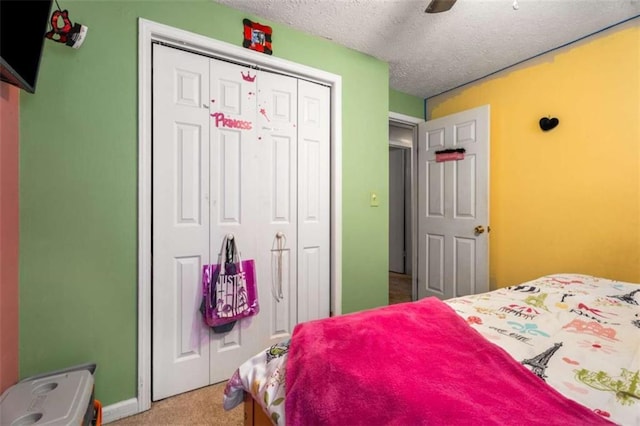 carpeted bedroom featuring ceiling fan, a closet, and a textured ceiling