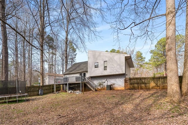 back of house featuring a fenced backyard, stairway, a trampoline, and a deck