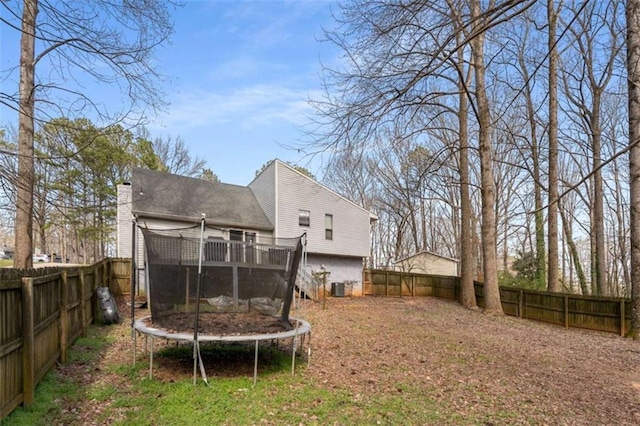 back of house with a trampoline, a fenced backyard, and a wooden deck