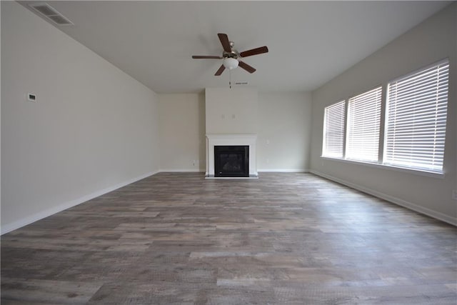 unfurnished living room with wood finished floors, baseboards, visible vents, a fireplace, and ceiling fan