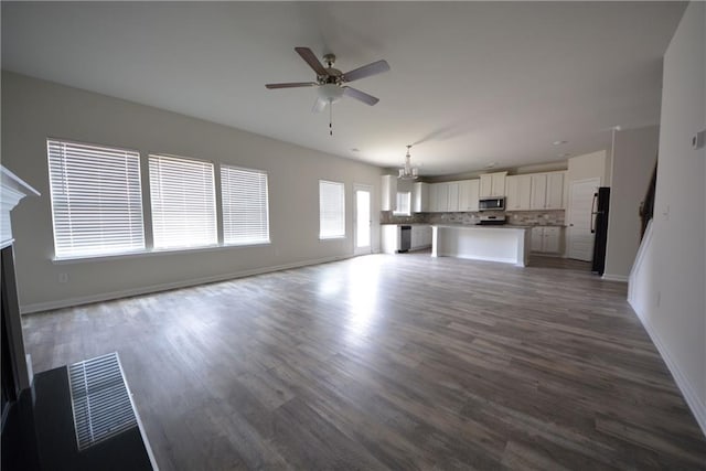 unfurnished living room with baseboards, wood finished floors, ceiling fan, and a fireplace