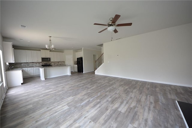 unfurnished living room featuring visible vents, light wood-style floors, and stairway