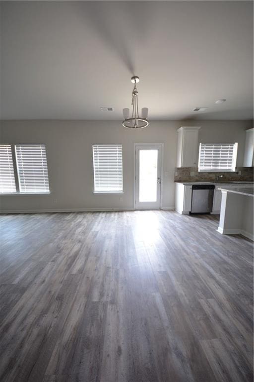 unfurnished living room with an inviting chandelier and dark wood-type flooring