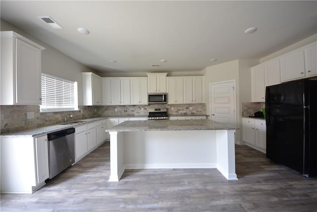 kitchen with white cabinetry, appliances with stainless steel finishes, a center island, and light wood-style floors