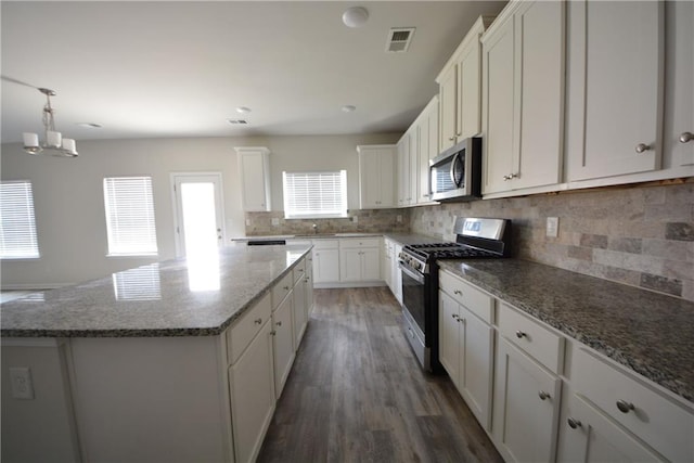 kitchen featuring visible vents, a kitchen island, white cabinetry, appliances with stainless steel finishes, and decorative backsplash