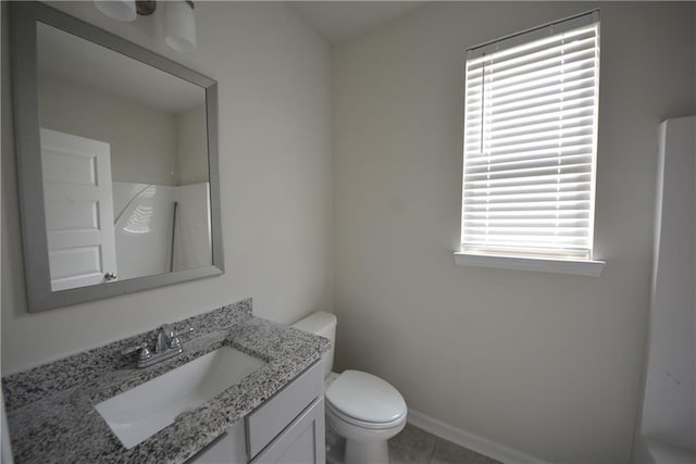 bathroom featuring vanity, toilet, baseboards, and tile patterned flooring