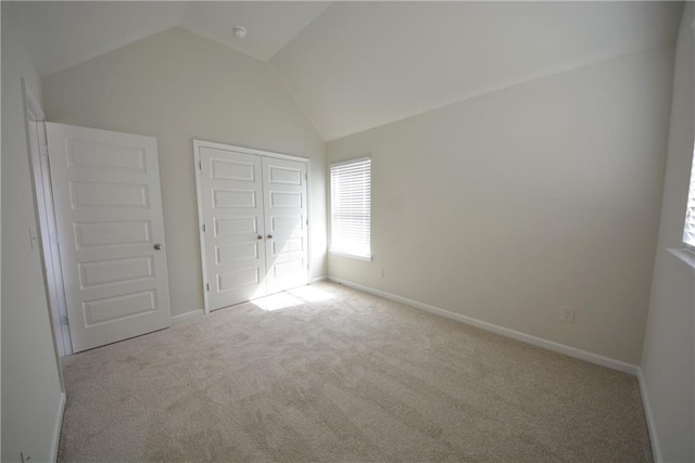 unfurnished bedroom with vaulted ceiling, carpet flooring, and baseboards