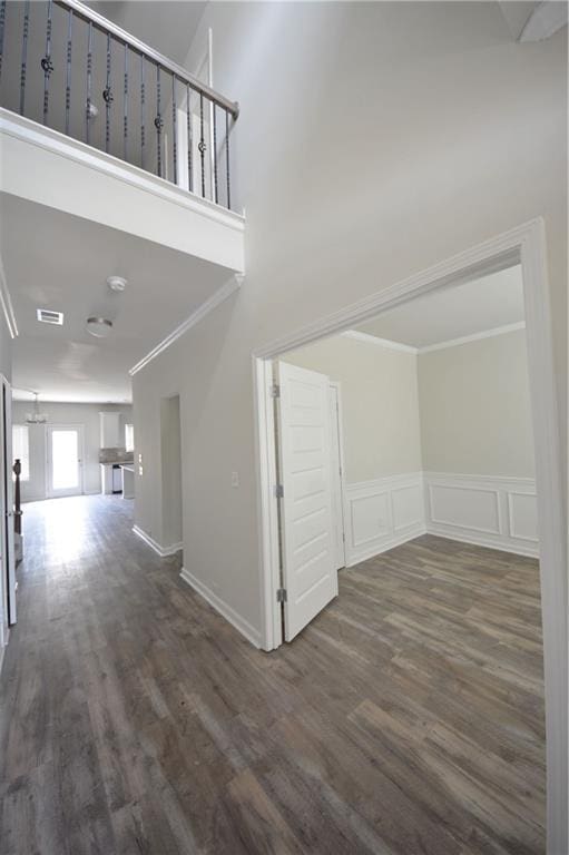 interior space featuring crown molding, a decorative wall, wood finished floors, and visible vents