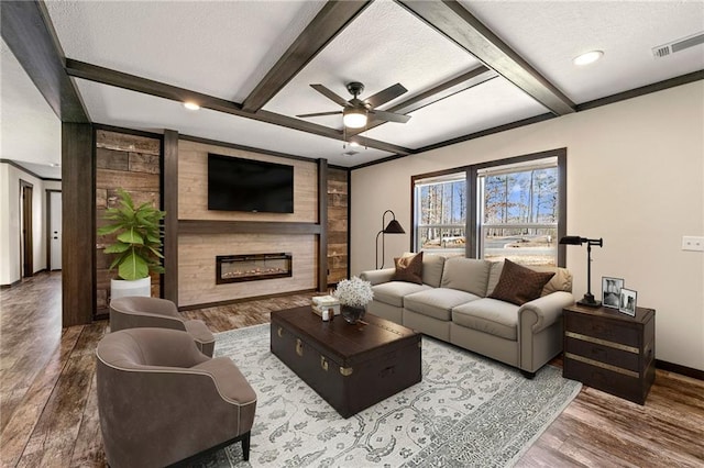 living area with beam ceiling, wood finished floors, visible vents, and a large fireplace