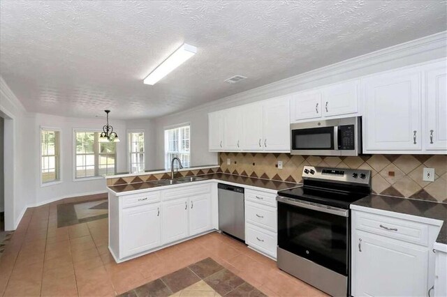 kitchen featuring sink, kitchen peninsula, tasteful backsplash, decorative light fixtures, and stainless steel appliances