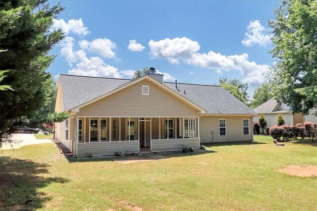 rear view of property featuring a yard and a sunroom