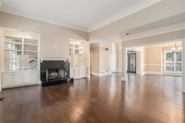 unfurnished living room featuring baseboards, a fireplace with raised hearth, dark wood finished floors, crown molding, and a chandelier