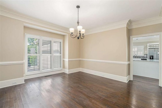 spare room with baseboards, crown molding, dark wood finished floors, and a notable chandelier