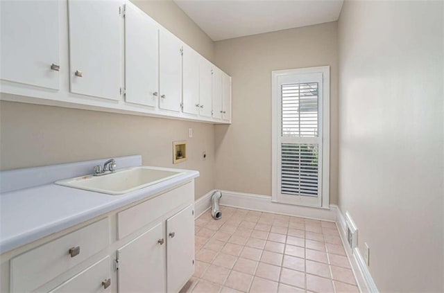 washroom featuring cabinet space, baseboards, washer hookup, a sink, and light tile patterned flooring