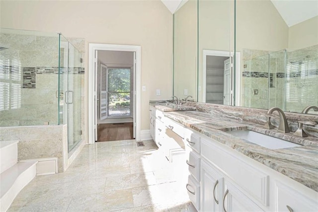 full bathroom featuring a garden tub, double vanity, lofted ceiling, a sink, and a shower stall