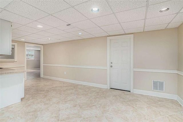 finished basement featuring a paneled ceiling, recessed lighting, visible vents, and baseboards