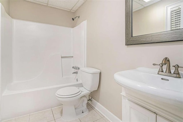 full bath with bathtub / shower combination, toilet, a drop ceiling, baseboards, and tile patterned floors