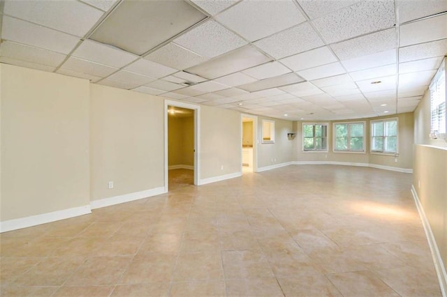 spare room with a paneled ceiling, light tile patterned floors, and baseboards