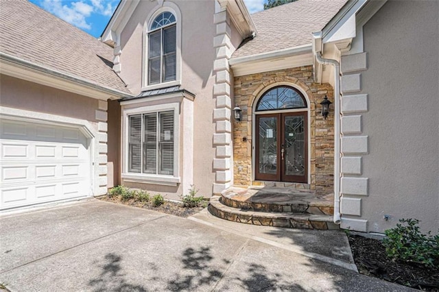 doorway to property featuring a shingled roof, stone siding, french doors, and stucco siding