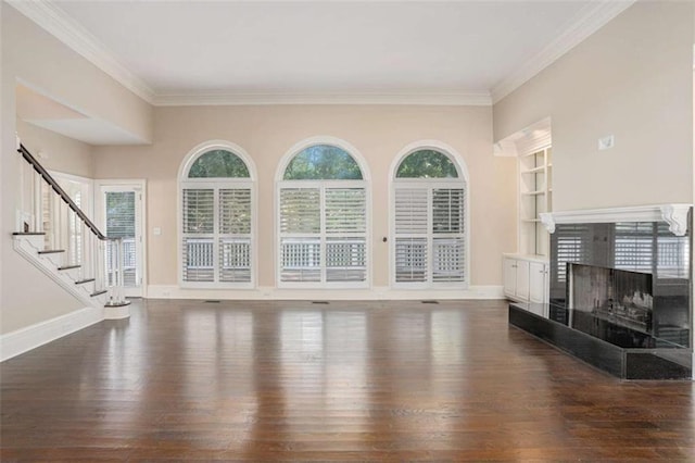 unfurnished living room with built in features, dark wood-style flooring, stairway, a tiled fireplace, and baseboards