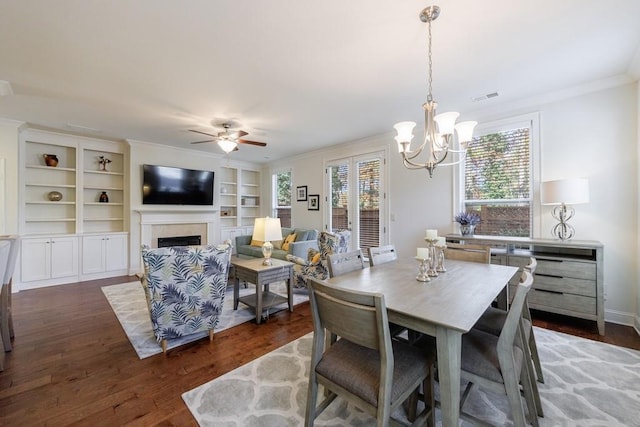 dining space with ceiling fan with notable chandelier, dark hardwood / wood-style flooring, and crown molding