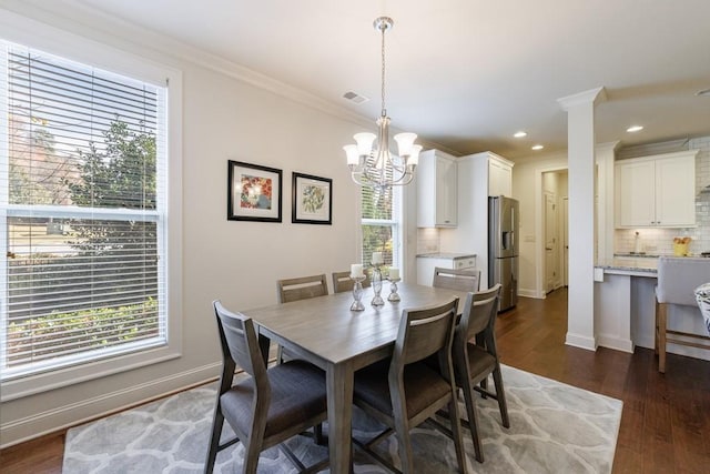 dining room with a wealth of natural light, dark hardwood / wood-style flooring, crown molding, and a notable chandelier