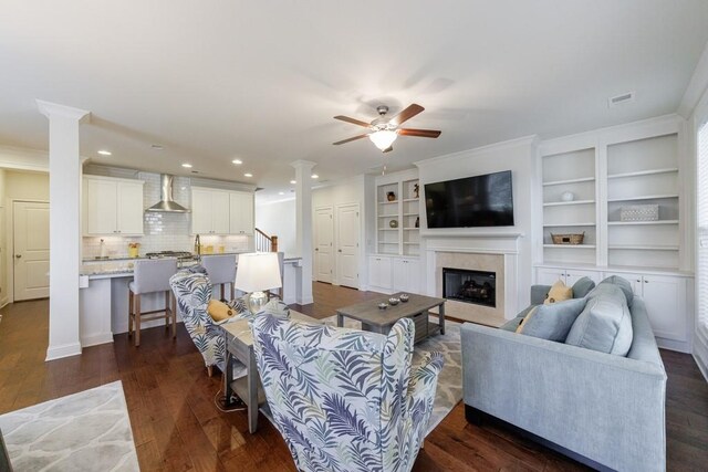 living room with ceiling fan, crown molding, and dark wood-type flooring