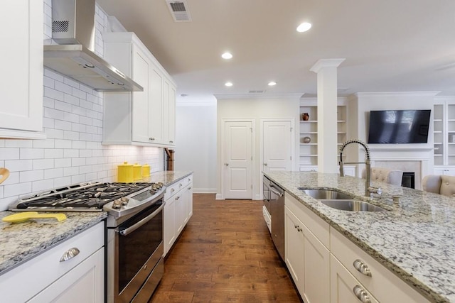 kitchen featuring dark hardwood / wood-style flooring, light stone counters, wall chimney exhaust hood, stainless steel appliances, and sink