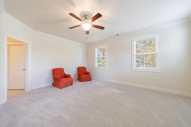 sitting room featuring ceiling fan, light colored carpet, a healthy amount of sunlight, and ornamental molding