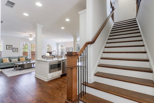 staircase with decorative columns, crown molding, ceiling fan, and hardwood / wood-style flooring