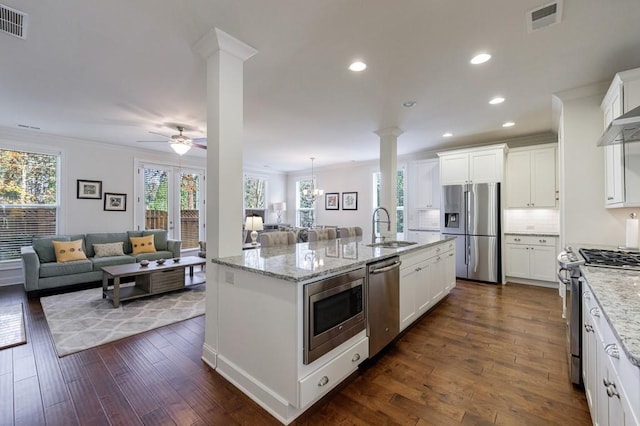 kitchen with appliances with stainless steel finishes, a kitchen island with sink, dark wood-type flooring, sink, and white cabinetry