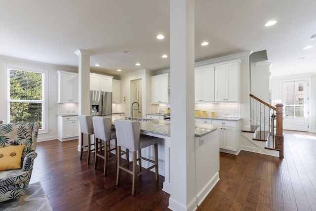 kitchen with a kitchen island with sink, white cabinets, and dark wood-type flooring