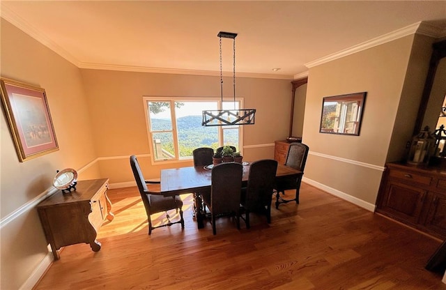 dining area featuring crown molding, wood-type flooring, and a notable chandelier