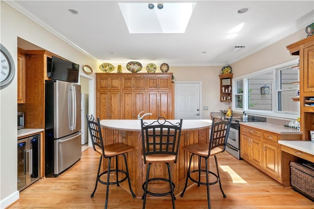 kitchen with light hardwood / wood-style flooring, a skylight, wine cooler, a center island, and stainless steel appliances