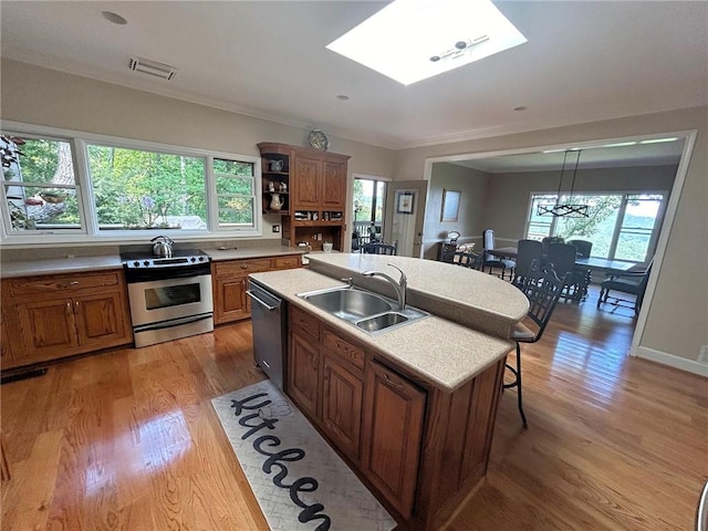 kitchen featuring sink, a skylight, appliances with stainless steel finishes, and light hardwood / wood-style floors