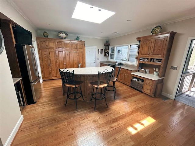 dining space featuring a skylight, light hardwood / wood-style floors, and ornamental molding