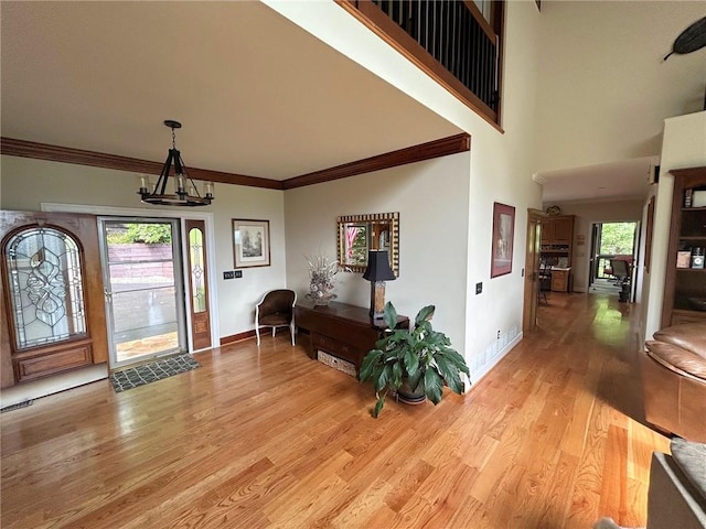 entrance foyer with a wealth of natural light, light hardwood / wood-style flooring, a chandelier, and ornamental molding