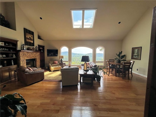 living room featuring hardwood / wood-style flooring, high vaulted ceiling, and a stone fireplace