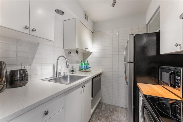 kitchen with range, tile walls, stainless steel dishwasher, sink, and white cabinets