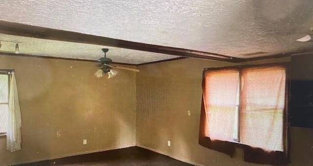 spare room featuring a ceiling fan, beamed ceiling, and a textured ceiling