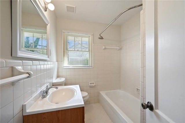 full bathroom with toilet, tile walls, visible vents, and a wealth of natural light