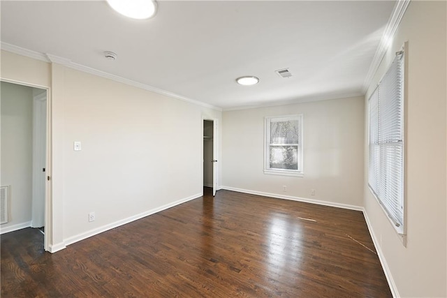 spare room featuring baseboards, wood finished floors, visible vents, and crown molding