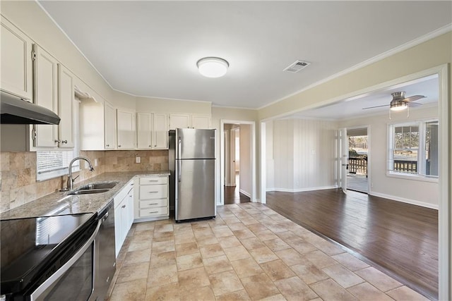 kitchen with light stone counters, stainless steel appliances, visible vents, ornamental molding, and a sink